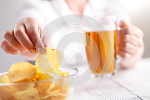 Female drink beed and eat heap of potato chips