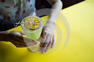 female drinking fresh green cocktail with pisang liquor, orange in bar or cafe