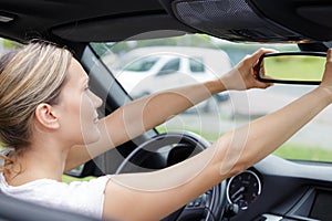 female driver adjusting rear view mirror