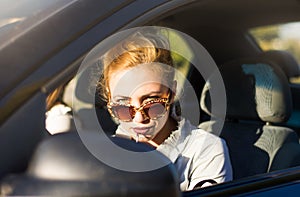 Female driver applying lipstick in a car