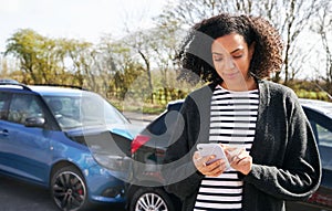 Female Driver Contacting Car Insurance Company On Mobile Phone After Road Traffic Accident