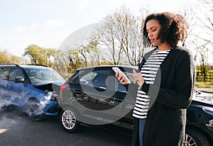 Female Driver Contacting Car Insurance Company On Mobile Phone After Road Traffic Accident