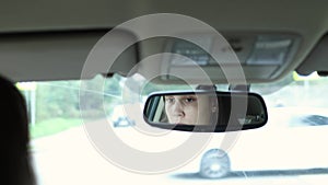 female driver face eyes in mirror. young woman driving car on crossroad, looking