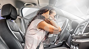 Female driver with headache or in desperation holds her head with both hands sitting on a driver& x27;s seat