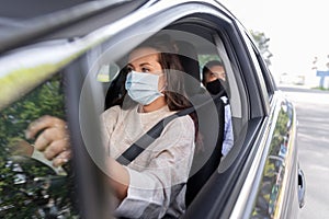 female driver in mask driving car with passenger