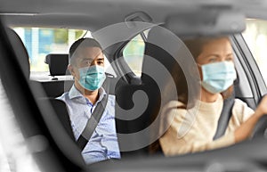 female driver in mask driving car with passenger