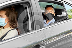 female driver in mask driving car with passenger