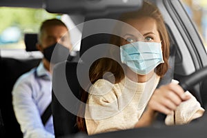 female driver in mask driving car with passenger