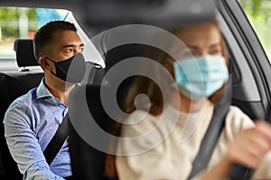 female driver in mask driving car with passenger