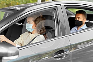 female driver in mask driving car with passenger
