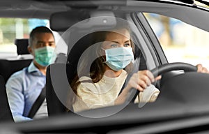 female driver in mask driving car with passenger