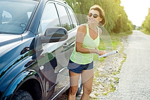 Female driver reading map near a car