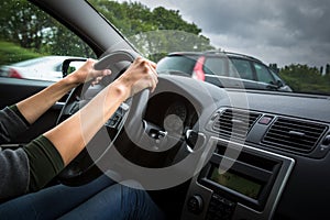 Female driver`s hands driving a car on a highway