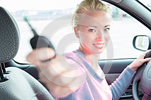 Female driver showing car keys. Young female driving happy about her new car or drivers license.