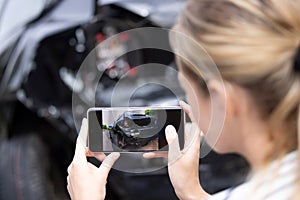 Female Driver Taking Photo Of Damaged Car After Accident For Insurance Claim On Mobile Phone photo