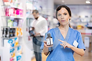 Female druggist presenting medicine in drugstore