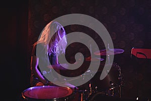 Female drummer performing on illuminated stage