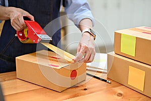 A female e-commerce business startup or worker packing her shipping box in stock room