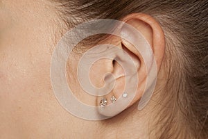 Female ear with three earrings