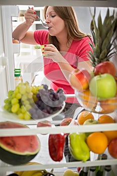 Female eat fruit yogurt from fridge