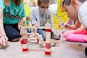 Female educator teaching children to build a train circuit