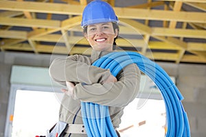 female el ectrician holding pipes in ceiling