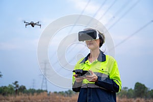 A female electrical engineer wearing vr goggles flying drone to explore aerial view equipment on high voltage pylons at power