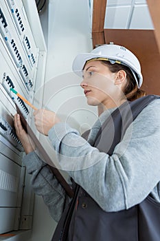 Female electrician checking distribution fuseboard