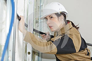 Female electrician fitting conduit in wall at construction site