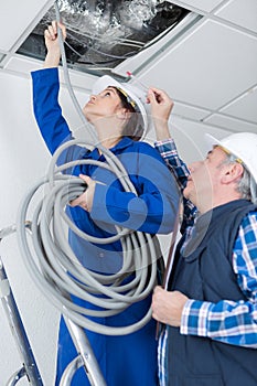 female electrician fixing ceiling lighting