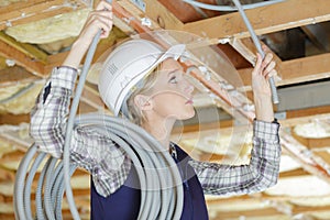 Female electrician fixing ceiling wiring
