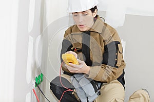 Female electrician installing electrical socket on wall