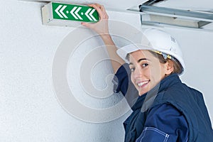 Female electrician installing emergency light