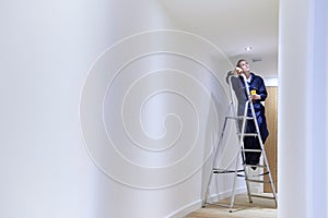Female Electrician Installing Lights In Ceiling