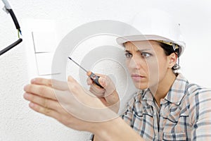 female electrician installing lightswitch