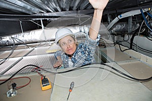 female electrician installing ventilation in ceiling