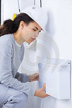 Female electrician installing wall radiator