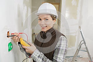 Female electrician installing wall socket