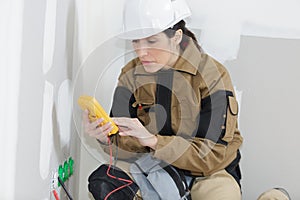 Female electrician installing wall socket