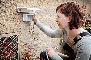 female electrician installs a socket outside in the garden