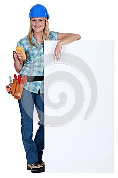Female electrician standing with advertising