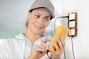 female electrician testing wall socket