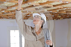 female electrician wiring inside ceiling