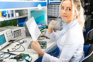 Female electronic engineer checking electronic circuit in laboratory