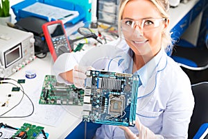 Female electronic engineer holding computer motherboard in hands
