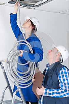 Female eleectrician putting pipes in ceiling