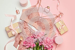 Female elegant pink lace bra and panties, pink candles, hair tie, a bouquet of beautiful peonies, nail polish, jewelry, top view