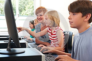 Female Elementary Pupil In Computer Class With Teacher