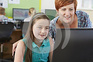 Female Elementary Pupil In Computer Class With Teacher