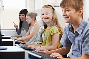 Female Elementary Pupil In Computer Class With Teacher